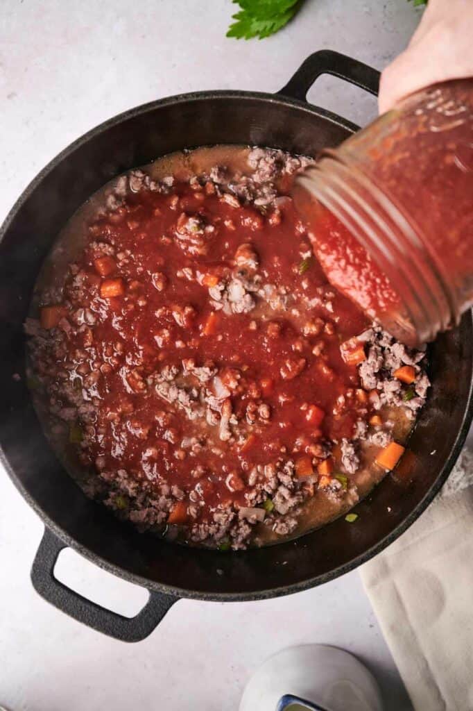 Tomato sauced poured into a skillet with beef.