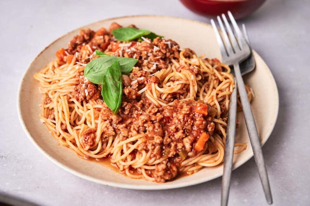Spaghetti Bolognese on a plate with forks on the side.