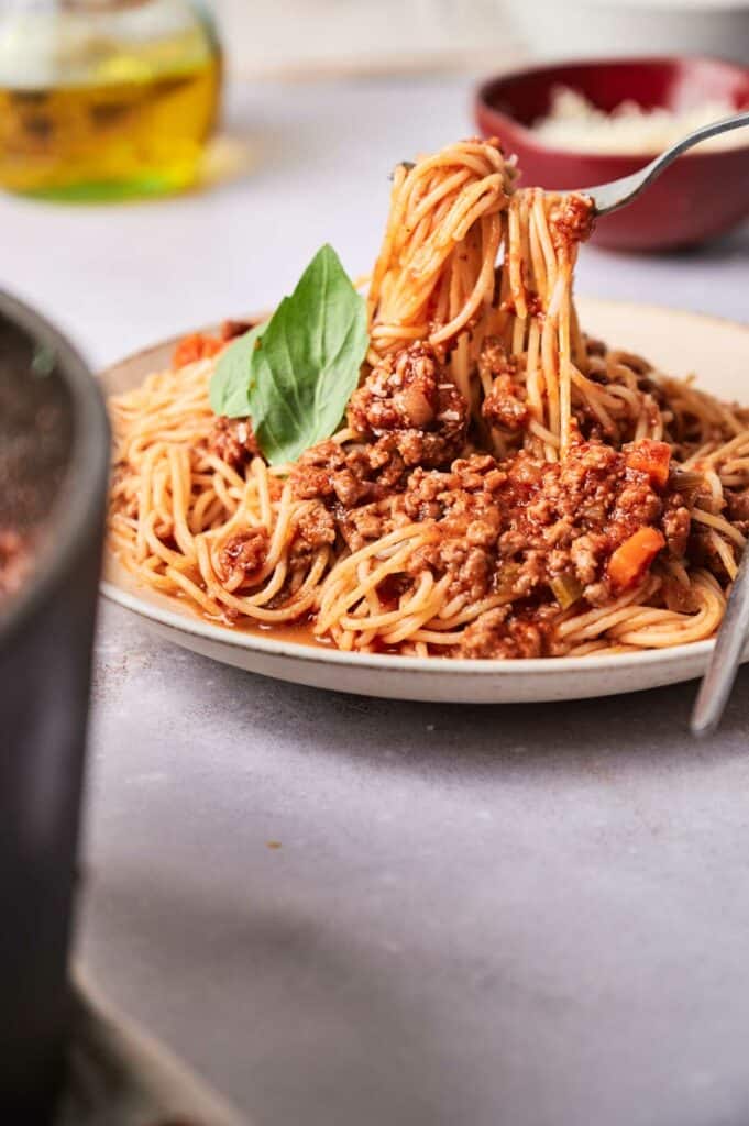 Spaghetti Bolognese on a plate with a fork lifting the pasta.