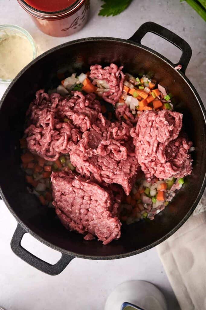 Ground beef being added in a pot.