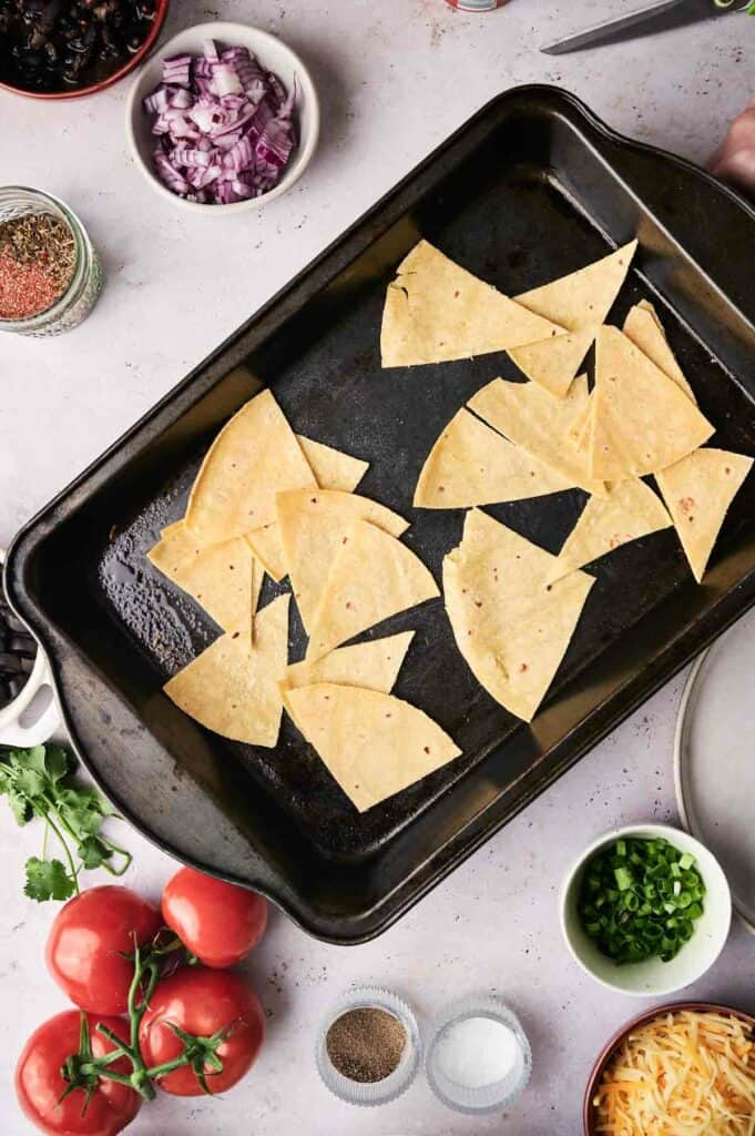 Tortilla chips layered on a baking tray.
