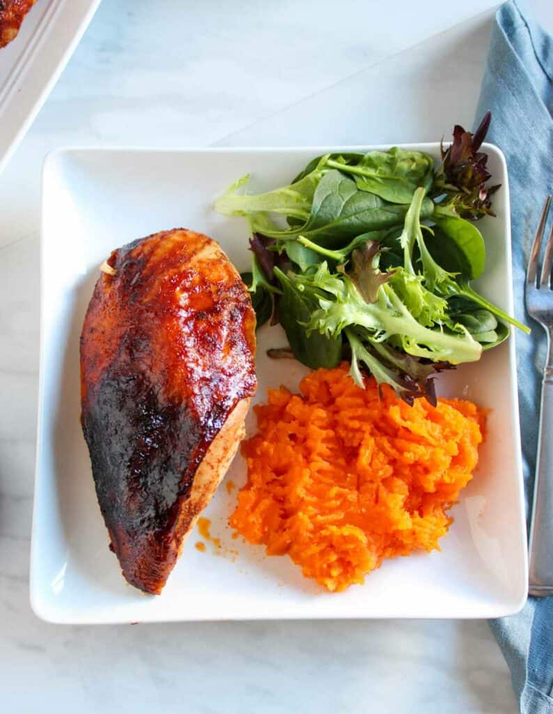 Baked chicken breast with a side of mashed sweet potatoes and mixed greens salad