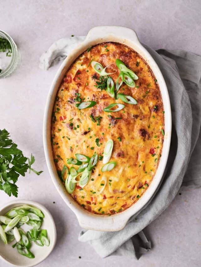 Baked casserole topped with green onions on a light background.