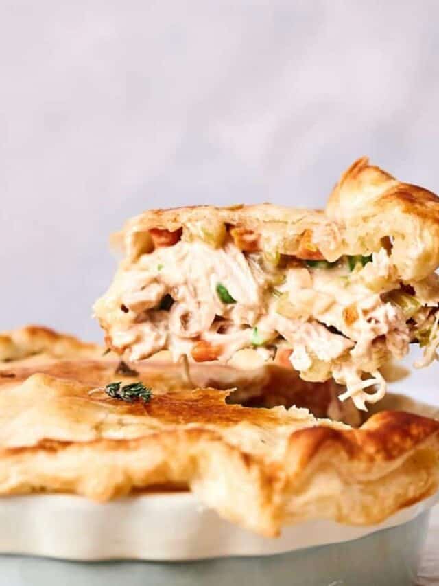 A chicken pot pie with a flaky crust, cut open to reveal a creamy chicken and vegetable filling.