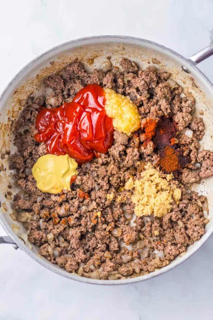 Ground meat sizzles in a skillet with ketchup, mustard, minced garlic, and seasonings simmering to perfection&mdash;ideal for delicious sloppy joe stuffed peppers.