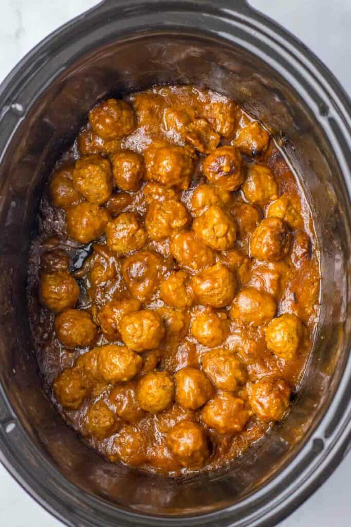 A slow cooker filled with Salisbury steak meatballs in a thick, sticky sauce.