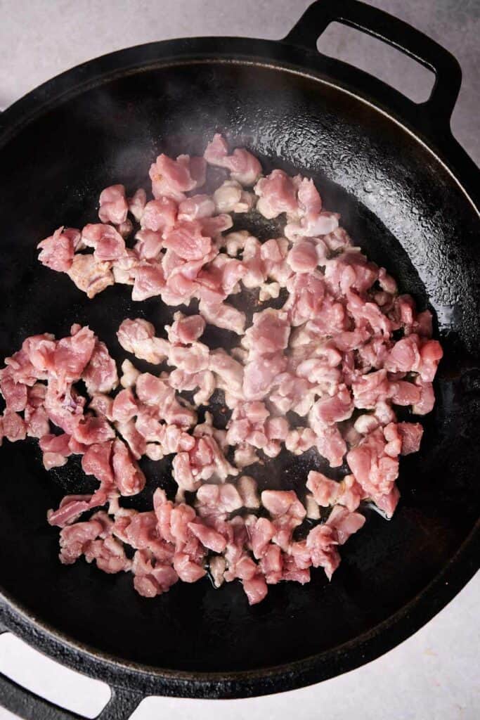 ground meat sizzle in a black cast iron skillet, reminiscent of the savory filling found in homemade tamales.