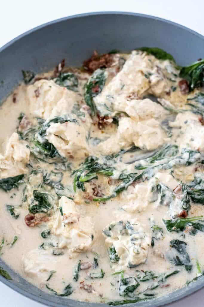 A pan of creamy spinach and artichoke dip with visible pieces of spinach and artichoke in a thick, white sauce, reminiscent of the rich flavors found in a bowl of Creamy Tuscan Pasta.