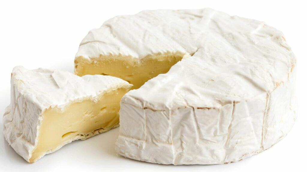 A wheel of brie cheese with a wedge cut out, showing the creamy interior and white rind.