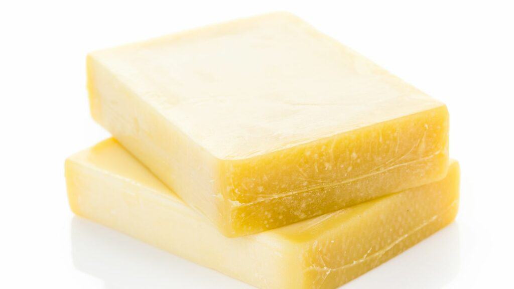 Two rectangular blocks of yellow cheese stacked on a white surface.