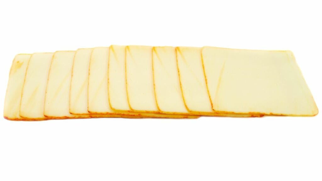 A stack of thinly sliced yellow cheese arranged in a row on a white background.