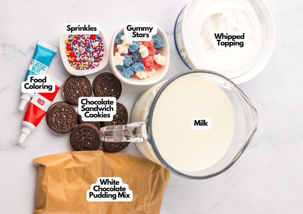 Ingredients on a counter: blue and red food coloring, rainbow sprinkles, Patriotic Gumdrops, gummy stars, whipped topping, milk, chocolate sandwich cookies, and white chocolate pudding mix.