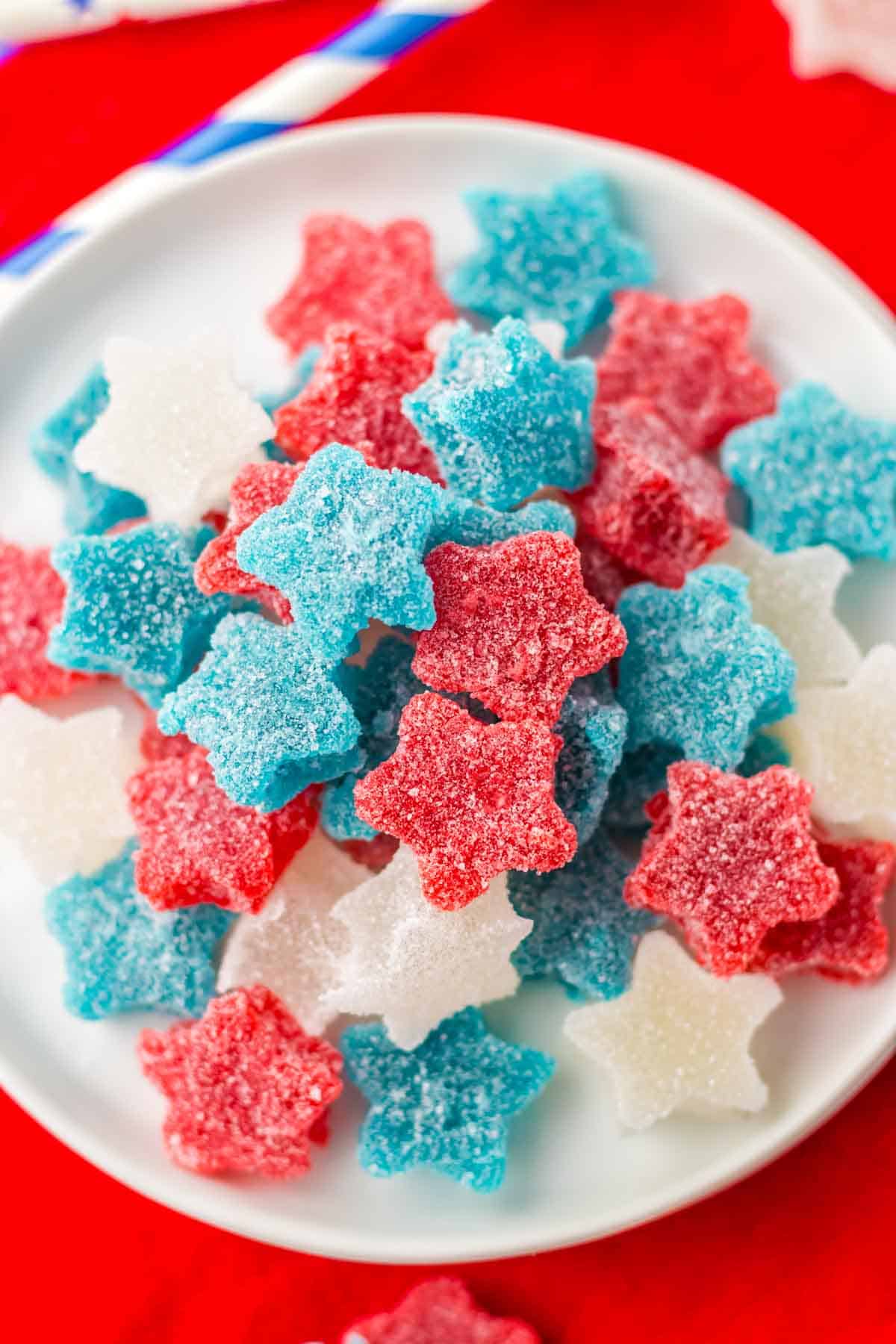 A plate filled with star-shaped red, white, and blue gummy candies covered in sugar.