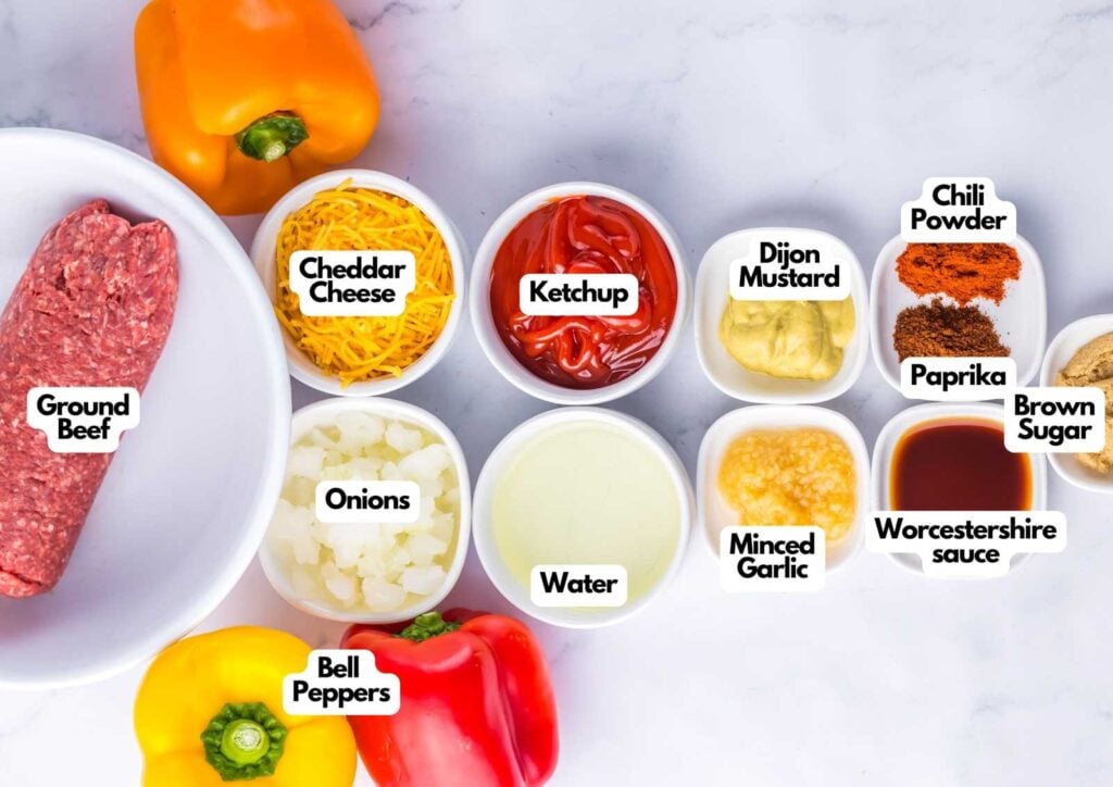 Ingredients for sloppy joe stuffed peppers are arranged on a marble surface, including ground beef, cheese, ketchup, mustard, spices, bell peppers, onions, garlic, water, and Worcestershire sauce.