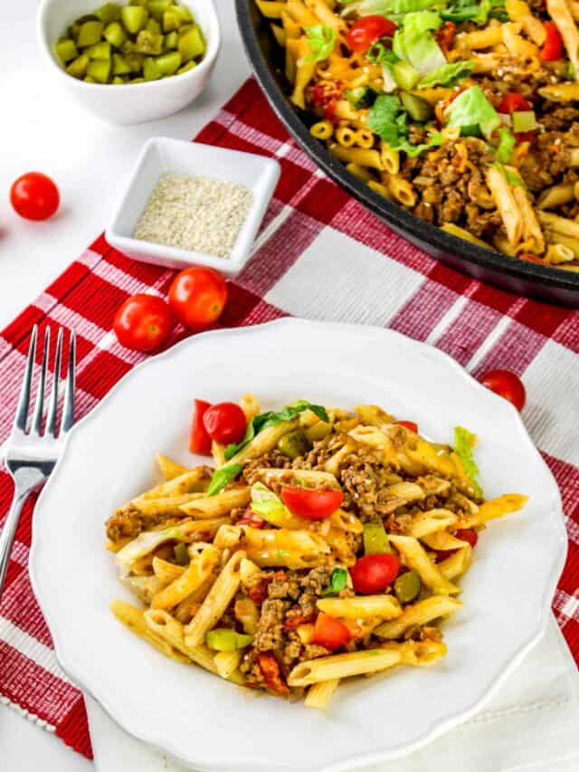 A plate of pasta with ground meat, diced tomatoes, and greens on a white plate. A pot of the same dish and ingredients such as cherry tomatoes, diced pickles, and seasoning are nearby on a red checkered cloth.