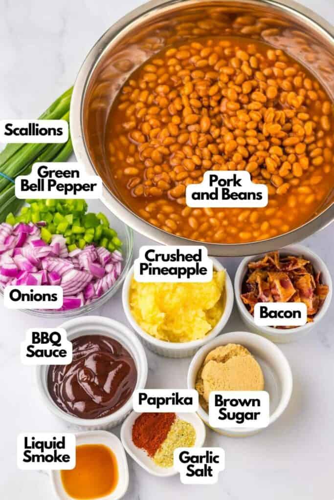 Ingredients for a Hawaiian baked beans dish are displayed in individual bowls, including scallions, green bell pepper, onions, BBQ sauce, bacon, crushed pineapple, paprika, brown sugar, garlic salt, and liquid smoke.
