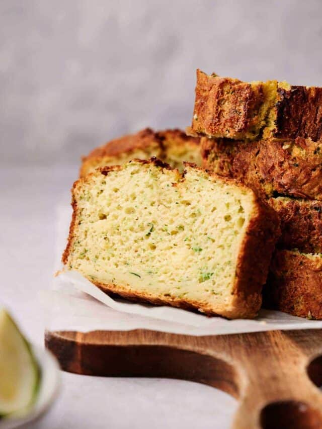 A sliced loaf of zucchini bread on a wooden cutting board.