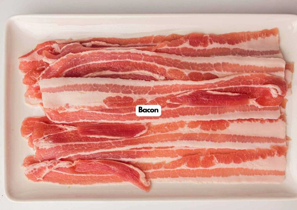 Several raw strips of bacon are neatly arranged on a rectangular white plate, ready to be made into delicious air fryer twisted bacon, viewed from above.
