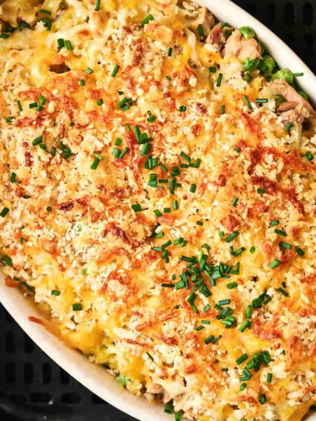 A close-up of a baked casserole topped with melted cheese, breadcrumbs, and chopped chives.