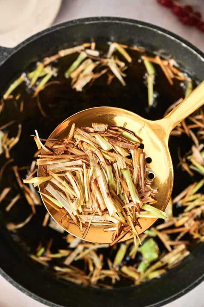 A ladle holds cooked lemongrass over a pot containing more lemongrass, creating an aromatic base that could easily accompany any dish, even deviled eggs.