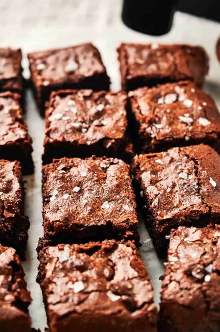 A close-up of freshly baked air fryer chocolate brownies with a crinkly top, sprinkled with sea salt, arranged in a grid pattern.