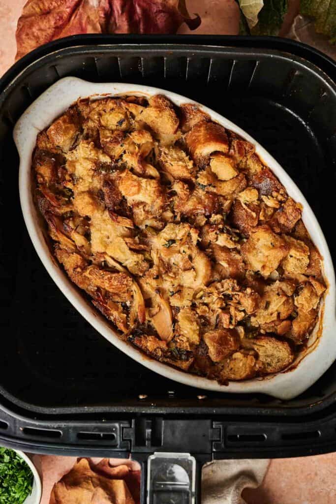 An air fryer Thanksgiving casserole features a delightful baked stuffing nestled in a classic oval dish, bringing warmth and flavor to your holiday feast.