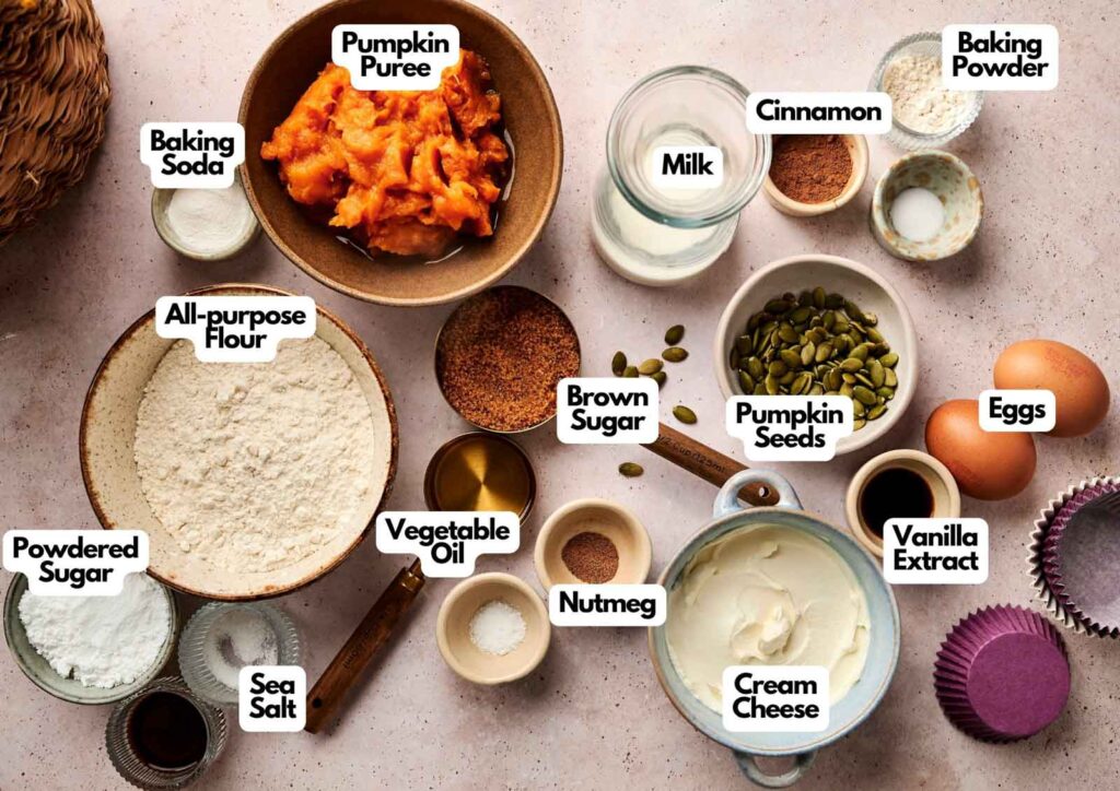 Assorted baking ingredients—including flour, eggs, pumpkin puree, cream cheese, brown sugar, milk, spices, baking powder, baking soda, oil, powdered sugar, and seeds—are arranged on a surface for recreating delicious Starbucks Pumpkin Cream Cheese Muffins at home.