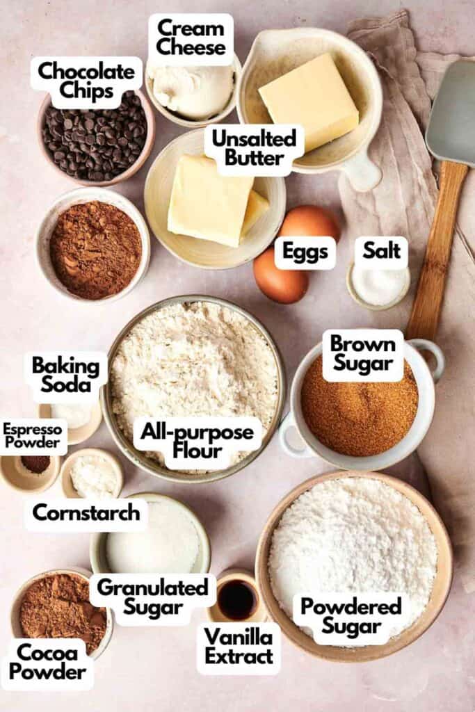 A delightful array of baking ingredients labeled for crafting Copycat Crumbl Chocolate Cake Cookies: chocolate chips, cream cheese, unsalted butter, eggs, salt, brown sugar, powdered sugar, vanilla extract, cocoa powder, granulated sugar, espresso powder, cornstarch, baking soda, and all-purpose flour.