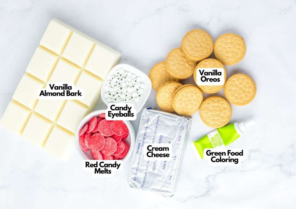 Vanilla almond bark, vanilla Oreos, red candy melts, cream cheese, candy eyeballs, and green food coloring create whimsical Spooky Halloween Eyeballs on a white surface.