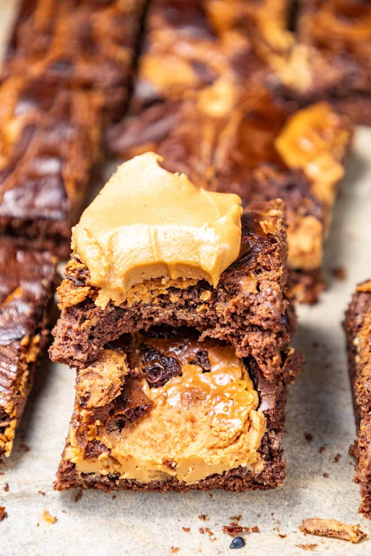 Close-up of a stack of decadent peanut butter brownies topped with creamy peanut butter on a baking sheet.