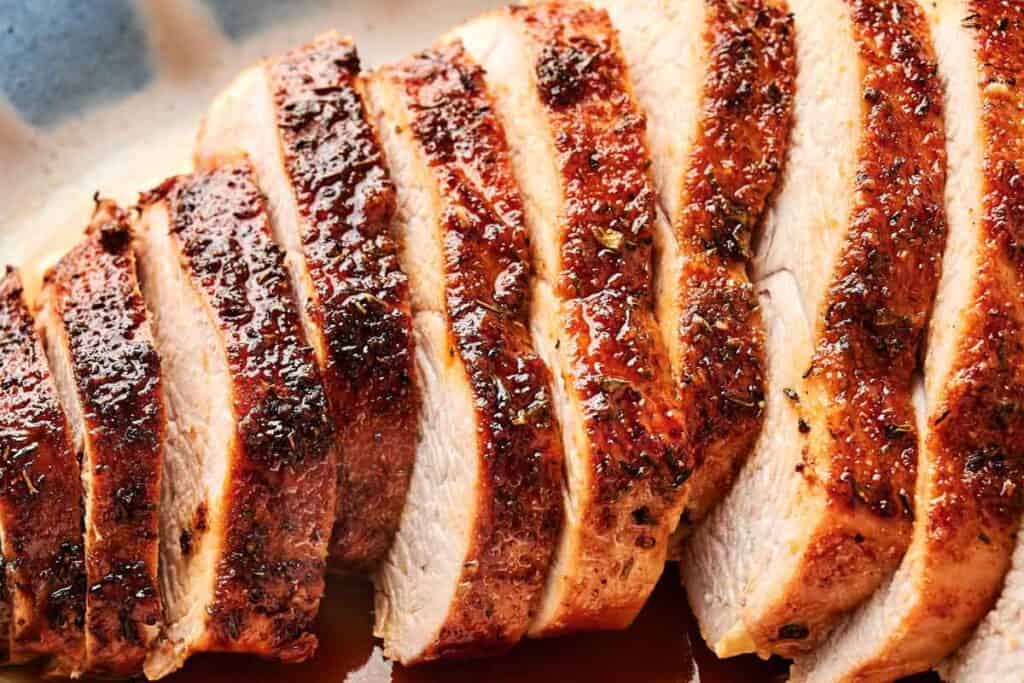 Sliced, seasoned, and roasted turkey breast arranged on a plate.