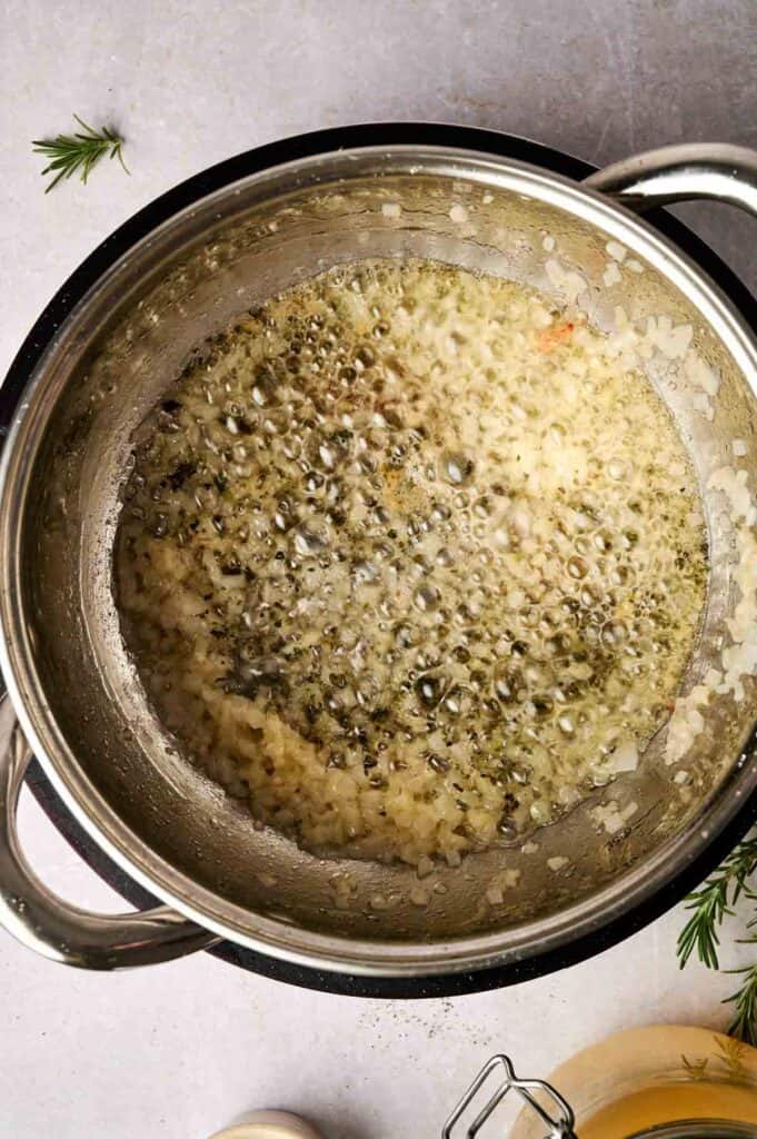 Chopped onions saut&eacute;ing in a pot with melted butter, herbs, and oil mingle to create the perfect base for a rich turkey gravy.