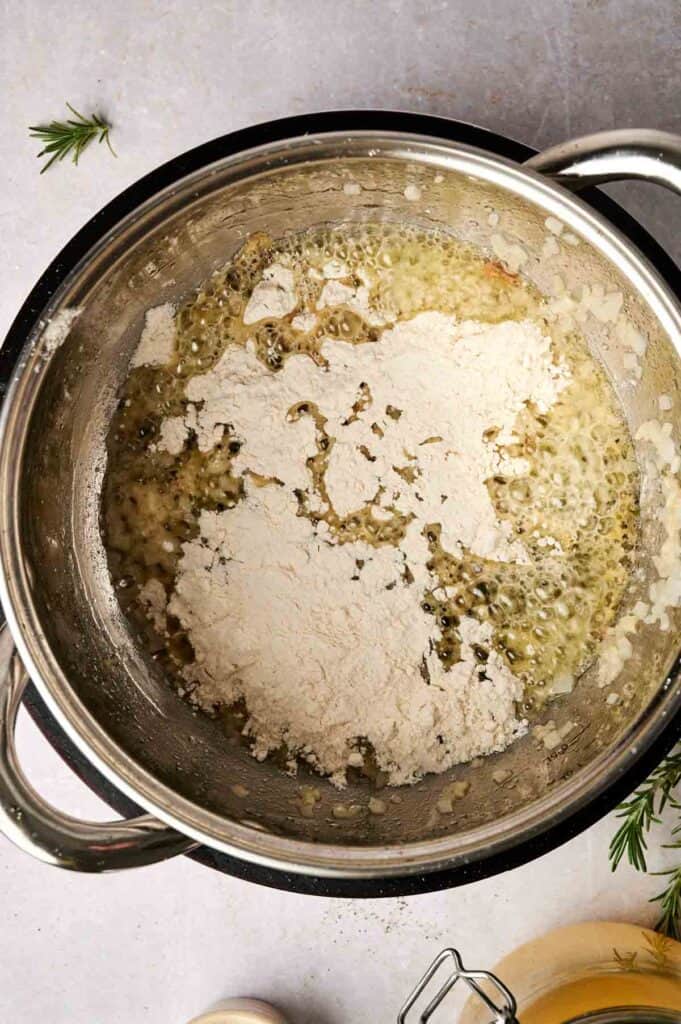 Flour mixed with butter in a pot on the stove, starting to form a light-colored roux perfect for rich turkey gravy.