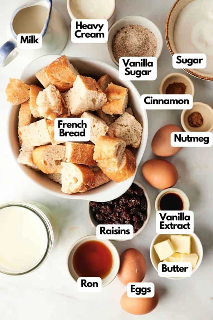 A delightful array for crafting classic bread pudding, featuring French bread, milk, heavy cream, sugar, cinnamon, nutmeg, eggs, vanilla extract, raisins, butter, and a splash of rum.