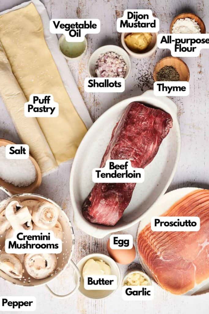 A classic Beef Wellington calls for beef tenderloin, puff pastry, prosciutto, cremini mushrooms, shallots, garlic, thyme, Dijon mustard, egg, butter, salt, pepper, and vegetable oil. This savory ensemble creates a dish worthy of any fine dining table.