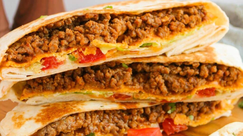 Close-up of stacked quesadillas filled with seasoned ground beef, melted cheese, and diced tomatoes.