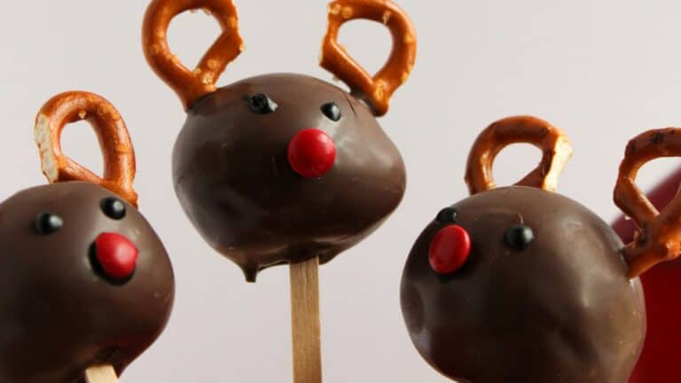 Chocolate cake pops decorated as reindeer with pretzel antlers and red candy noses.