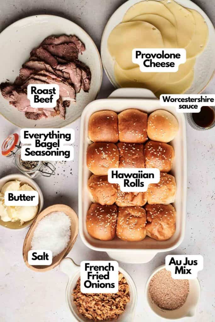 On the table are the essentials for crafting delicious Roast Beef Sliders: tender roast beef, savory provolone cheese, zesty Worcestershire sauce, everything bagel seasoning, buttered Hawaiian rolls, a dash of salt, crispy French fried onions, and rich au jus mix.