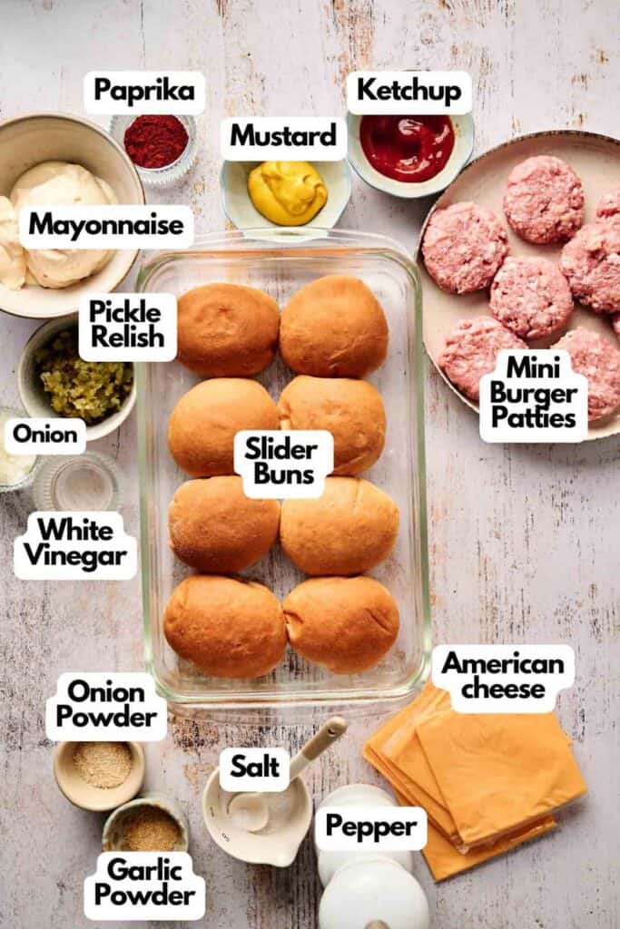 A top-down view showcases the ingredients for delicious cheeseburger sliders, featuring slider buns, mini burger patties, cheese, ketchup, mustard, mayonnaise, and an array of seasonings like paprika and garlic powder to enhance flavor.