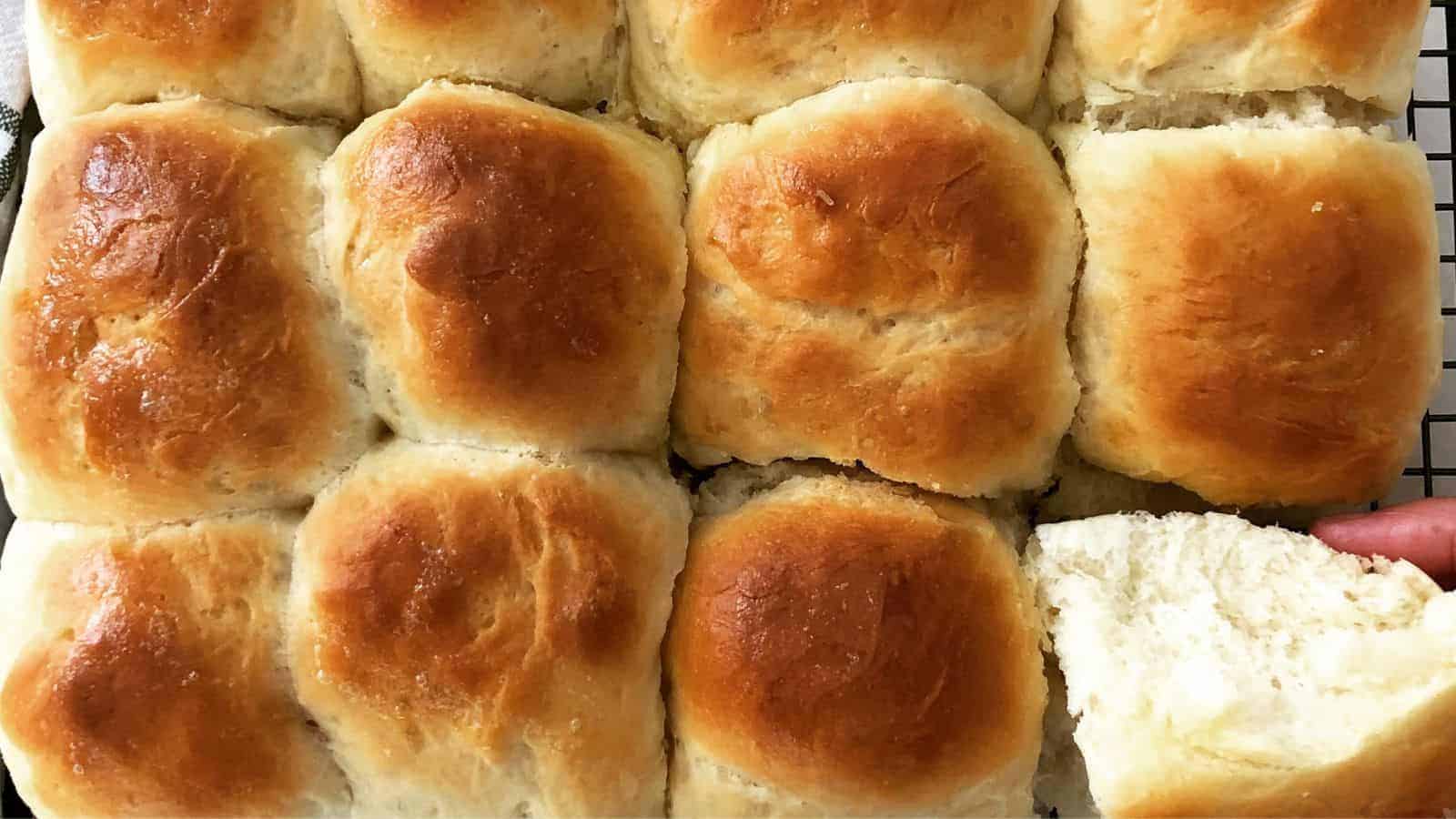 Close-up of freshly baked Ladi Pav on a wire rack, some split open to reveal a soft, fluffy interior.