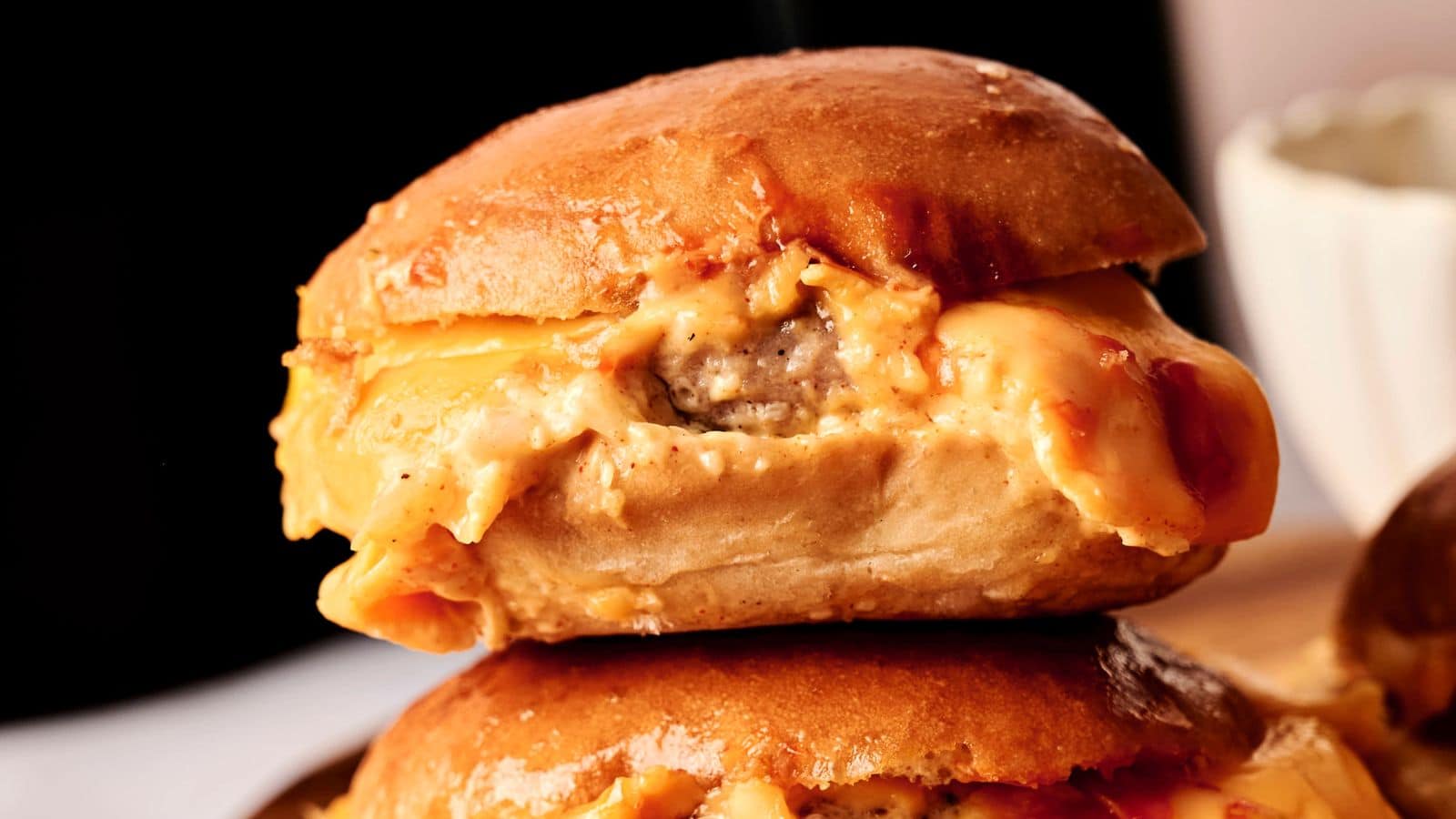 Close-up of a cheeseburger slider with melted cheese oozing out of a soft bun.