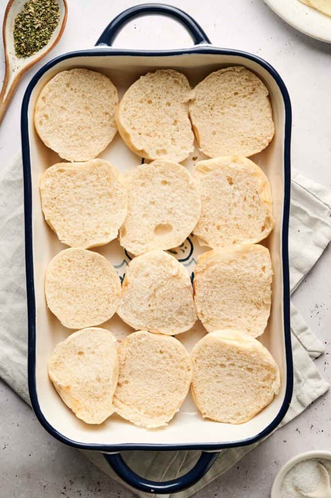 Sliced baguette pieces artfully arranged in a baking dish, perfect as a base for delectable meatball sliders.