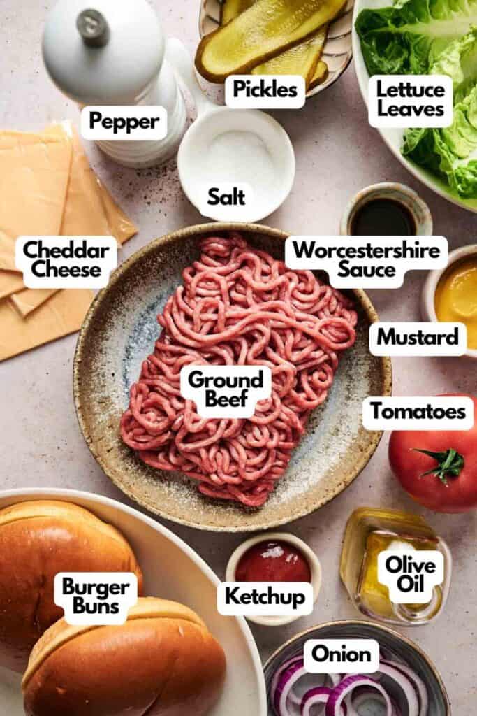 Ingredients for a delicious cheeseburger include ground beef, burger buns, cheddar cheese, pickles, lettuce, tomatoes, onion, Worcestershire sauce, mustard, ketchup, pepper, salt, and olive oil.