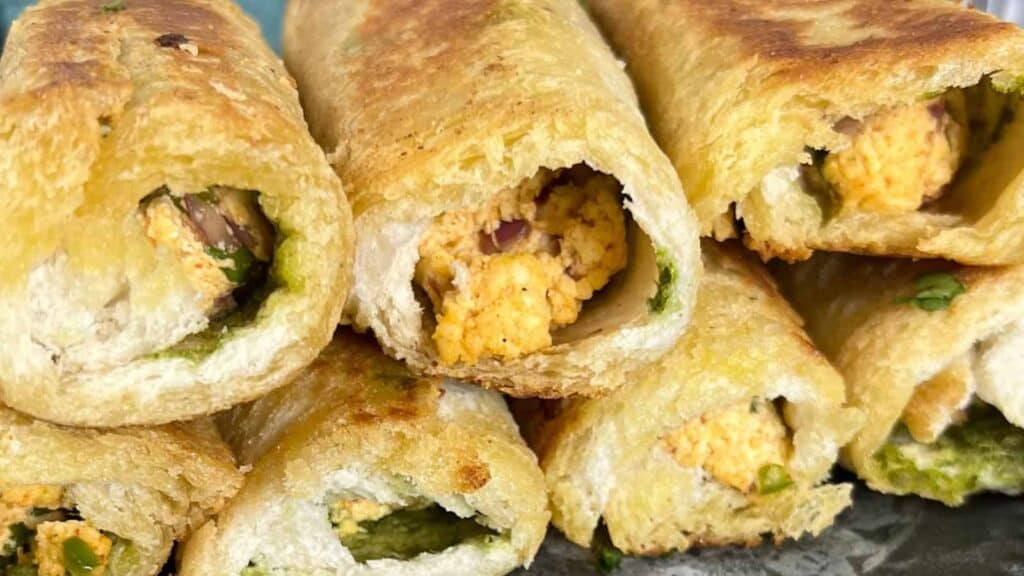 Close-up of stuffed bread rolls filled with spiced paneer and green chutney.