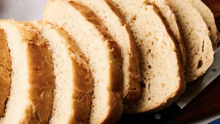 Slices of fresh bread on a cutting board, with a partially visible knife underneath.