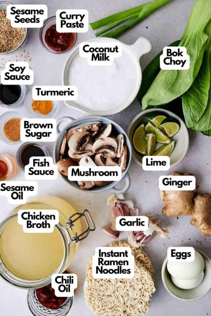 An assortment of ingredients for a ramen dish, including coconut milk, soy sauce, curry paste, fish sauce, sesame seeds, lime, ginger, mushrooms, instant noodles, bok choy, and more.