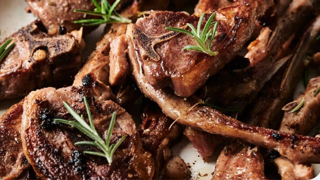 Cooked lamb chops garnished with fresh rosemary.