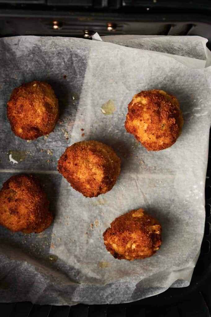 Five golden-brown Air Fryer Rattlesnake Bites gleam deliciously on parchment paper in their basket.