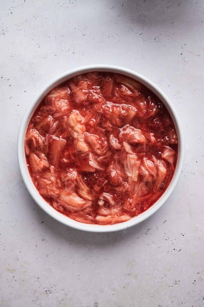 A bowl filled with pink grapefruit segments and juice on a light-colored surface evokes the refreshing essence of spring, reminiscent of a rhubarb crisp freshly baked to perfection.