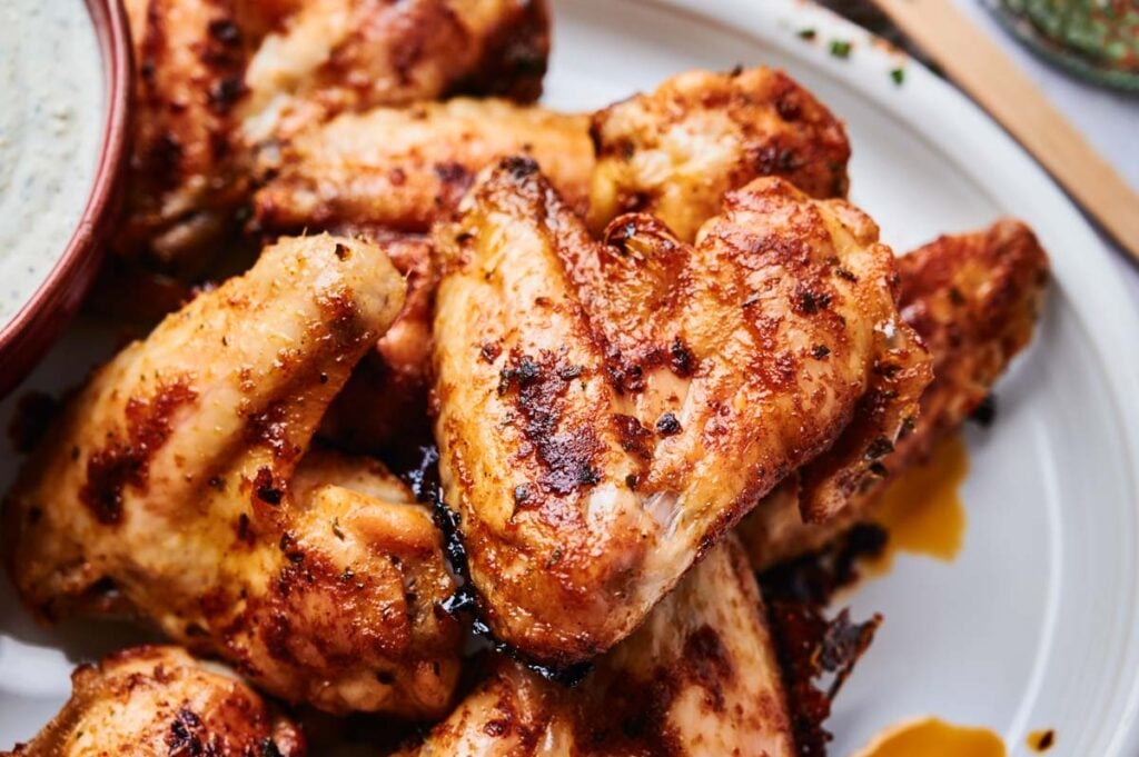 A close-up of Wingstop Louisiana Rub Wings, perfectly seasoned and grilled, served with a side dish of flavorful dipping sauce.
